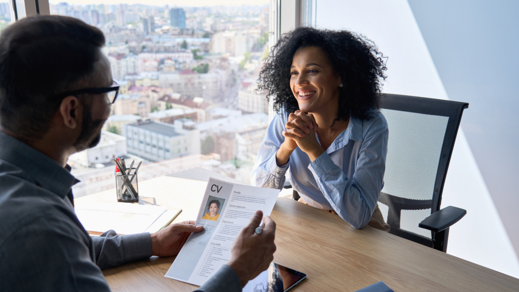 This is a picture of a woman being interviewed by a man. They are looking at a CV.